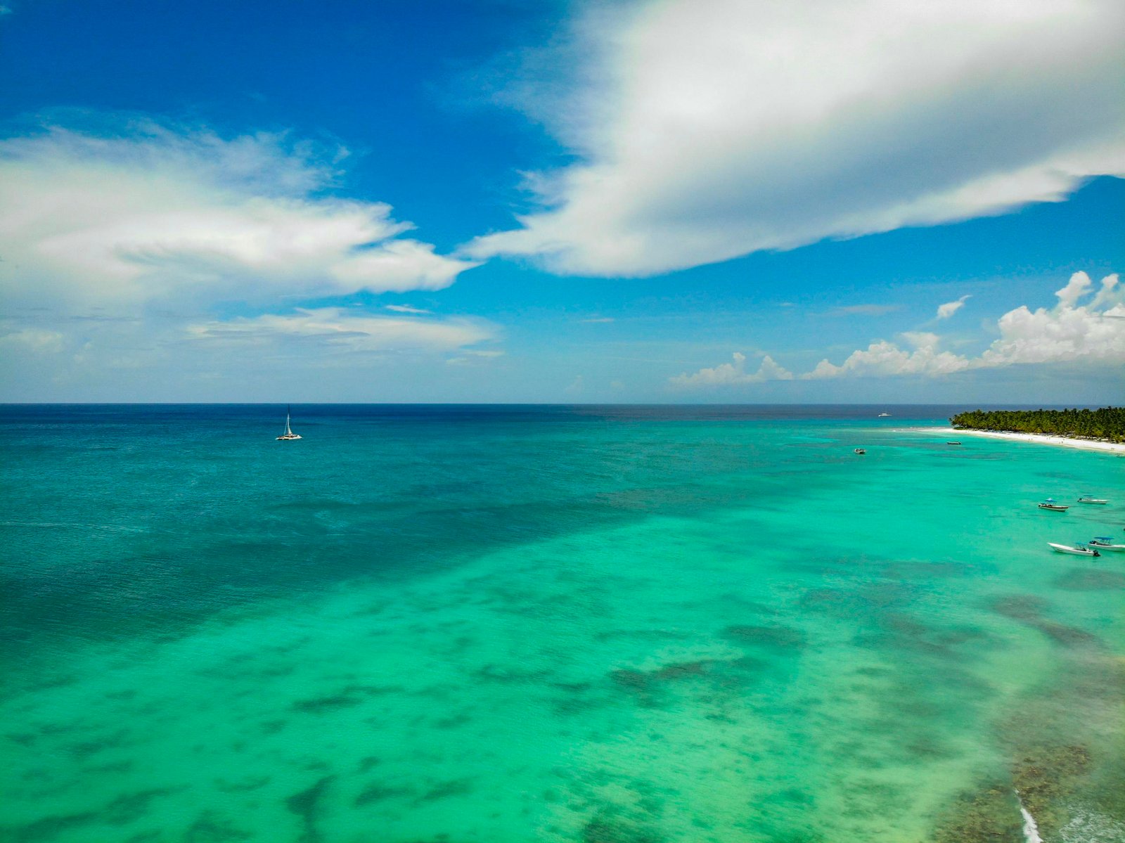 Breathtaking aerial view of a turquoise tropical beach with boats and a clear sky.